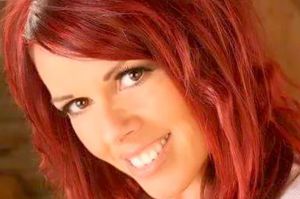 a woman with red hair is smiling and looking at the camera .