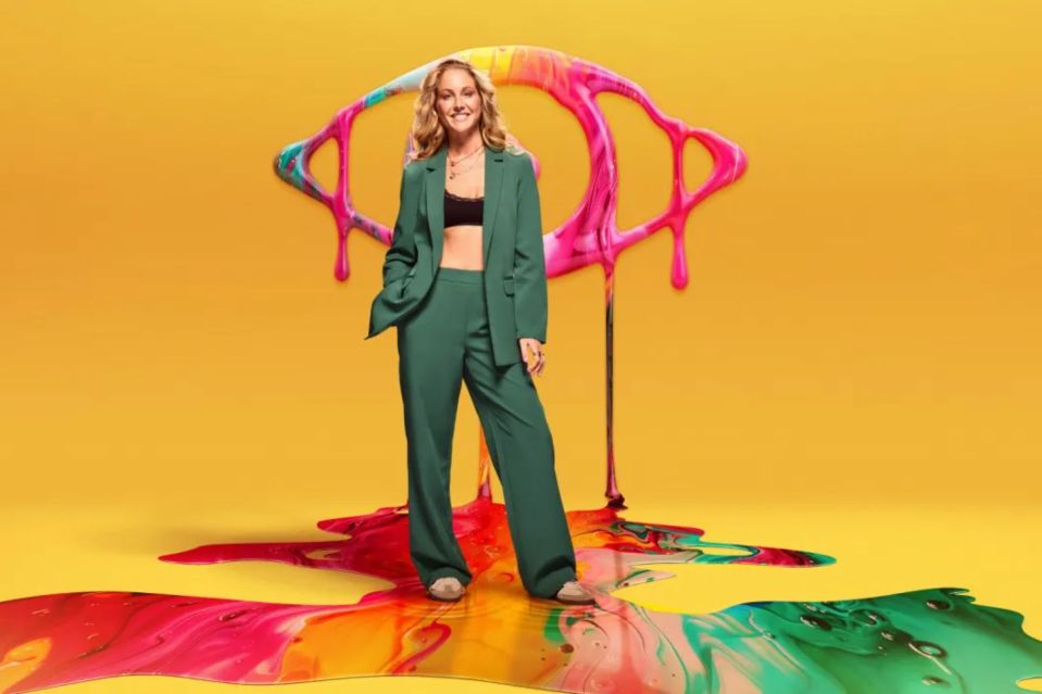 a woman in a green suit stands in front of a colorful eye