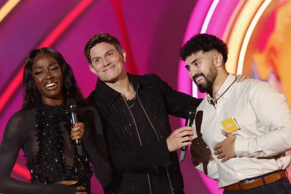 a man holding a microphone stands next to a woman and another man