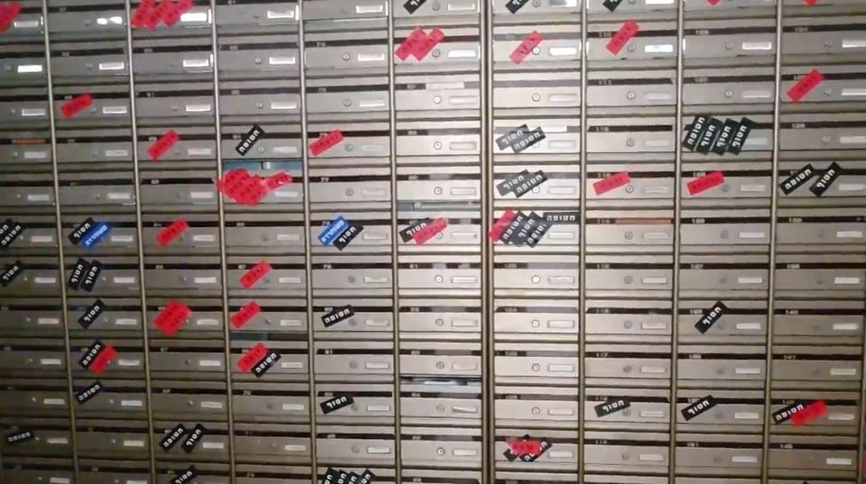 a wall of mailboxes with stickers on them including one that says stop