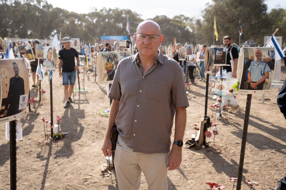 a man stands in front of a display of pictures of soldiers including one that says ' ariel ' on it