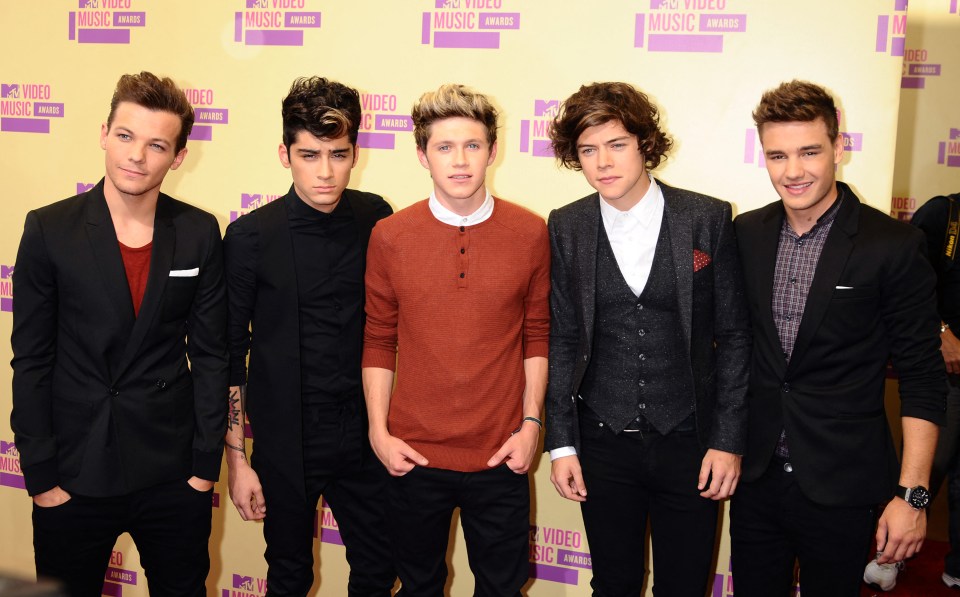 a group of men standing in front of a wall that says mtv video music awards