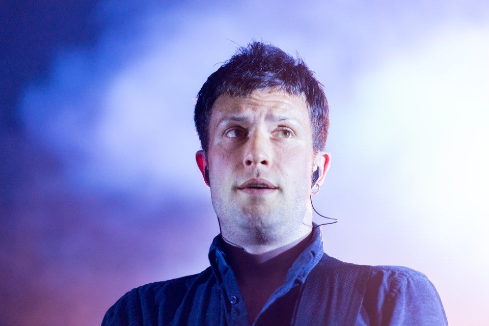 a man with ear buds around his neck looks to the side