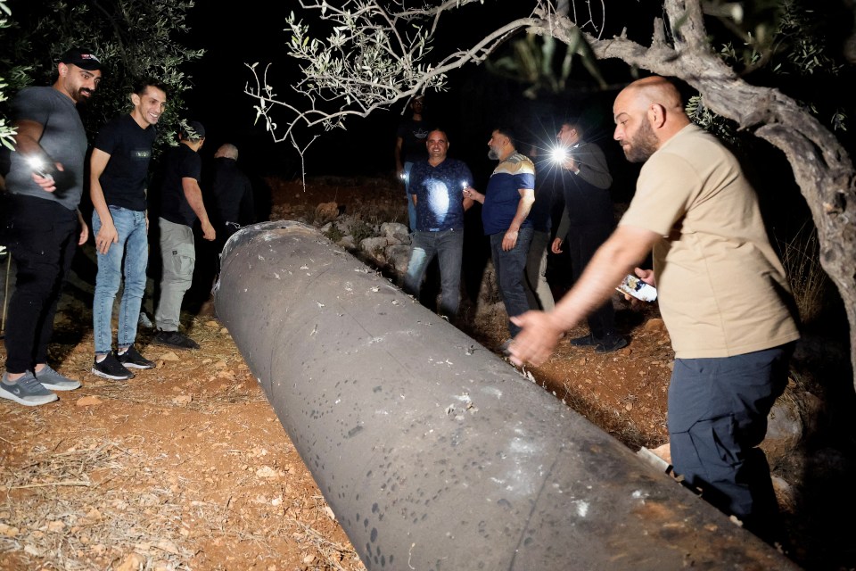 a group of men are standing around a large black pipe