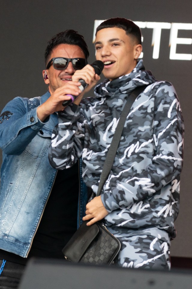 a man singing into a microphone next to a boy wearing a camo jacket