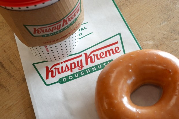 a krispy kreme doughnut sits next to a cup of coffee