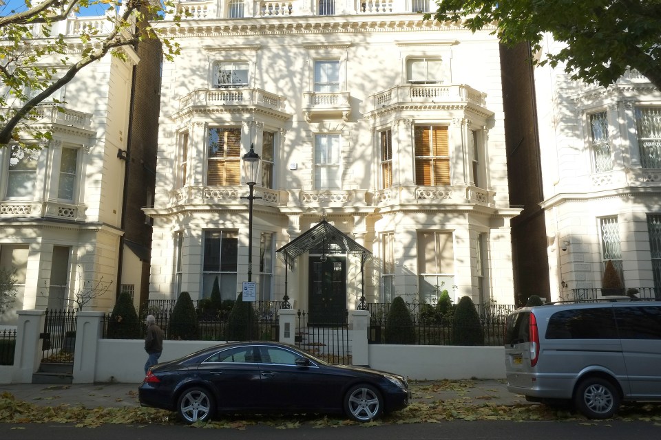 a black car is parked in front of a large white building