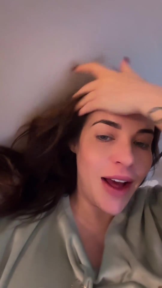a woman in a green shirt holds her hand to her forehead