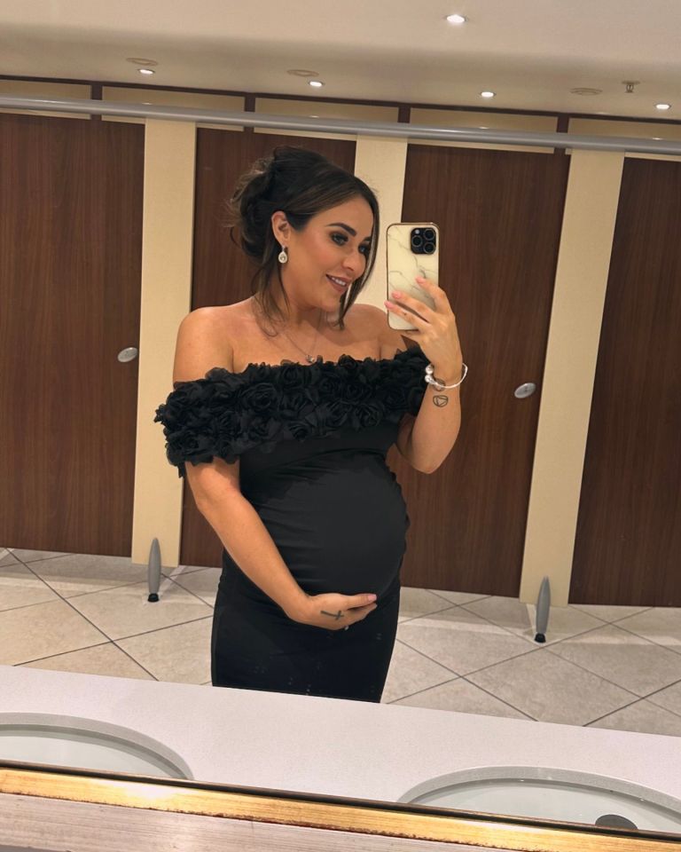 a pregnant woman taking a picture of herself in a bathroom mirror