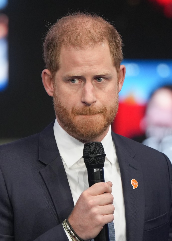 a man in a suit holds a microphone with a pin that says ' harry ' on it