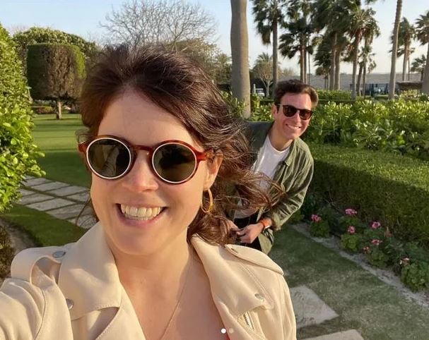 a man and a woman wearing sunglasses are standing next to each other in a park .