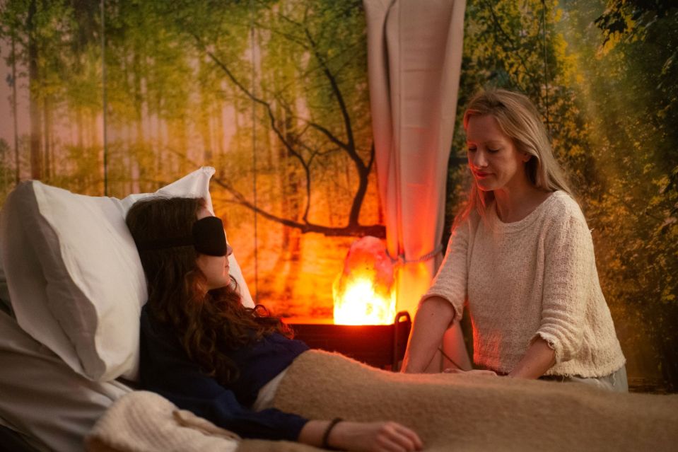 a woman in a white sweater is talking to a woman in a black eye mask