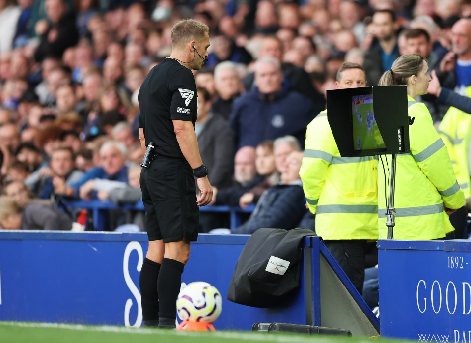 a soccer referee stands in front of a sign that says good