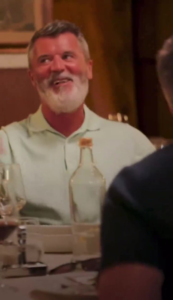 a man with a beard is sitting at a table with a bottle of wine .
