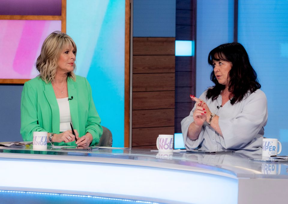 two women are sitting at a table with a cup that says ' wo ' on it