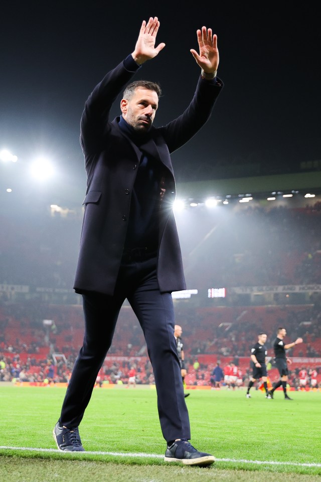 a man stands on a soccer field with his hands in the air