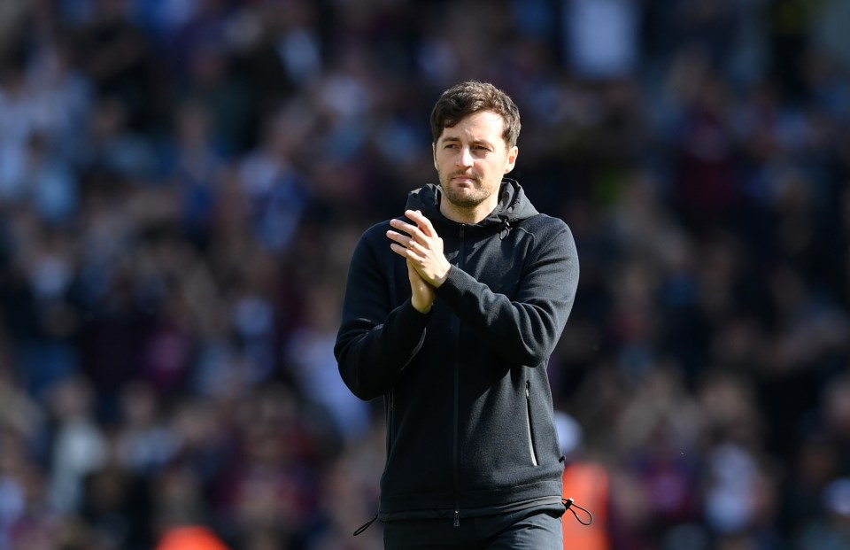 a man in a black jacket applauds the crowd