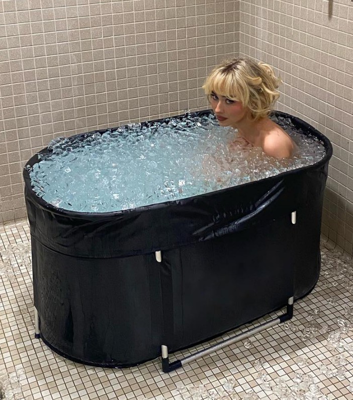 a woman is taking a bath in a tub filled with ice