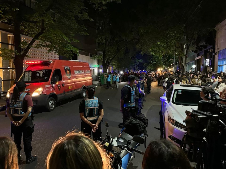 a red ambulance is parked in front of a crowd of people