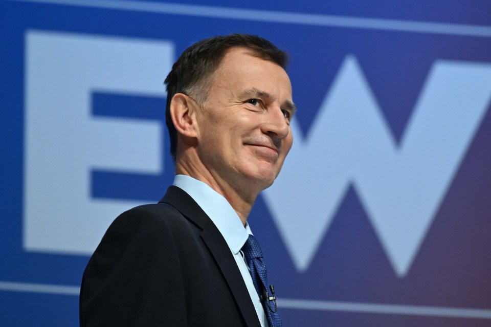 a man in a suit stands in front of a large ew sign
