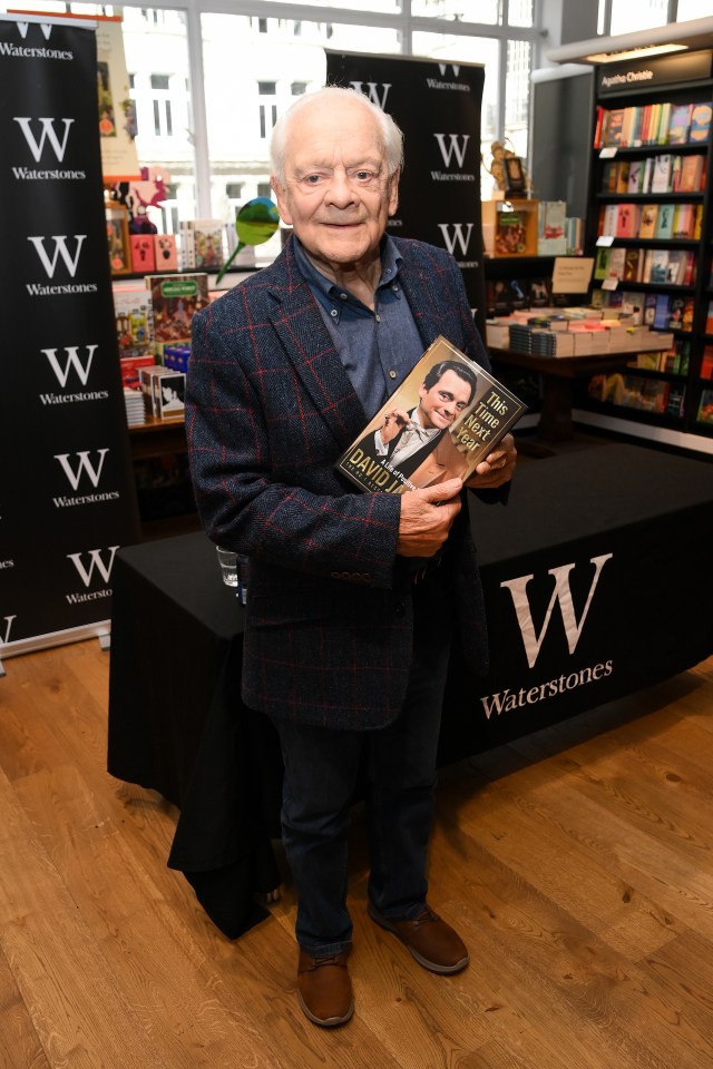 a man holding a book in front of a waterstones sign