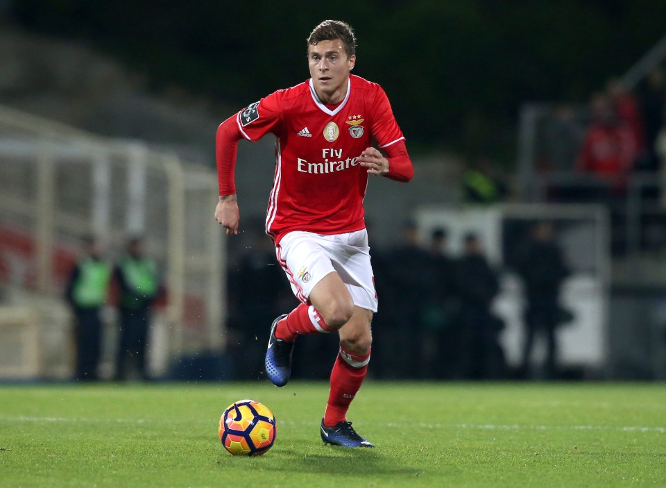 a soccer player wearing a fly emirates jersey runs with the ball