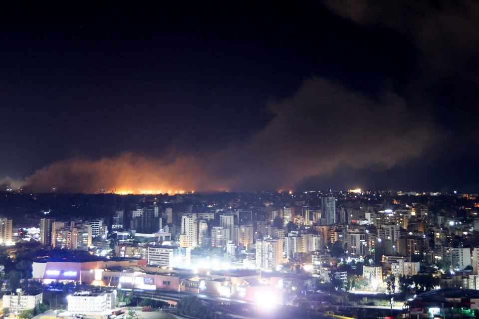 an aerial view of a city at night with smoke coming out of the sky