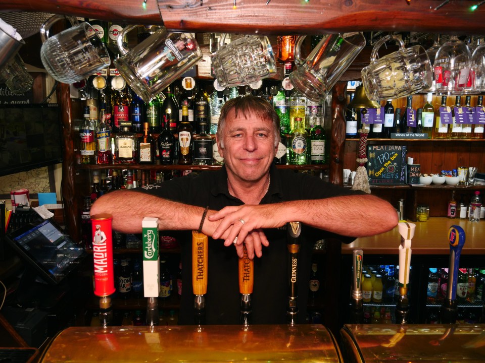 a man stands behind a bar with a tap that says hatcher 's on it