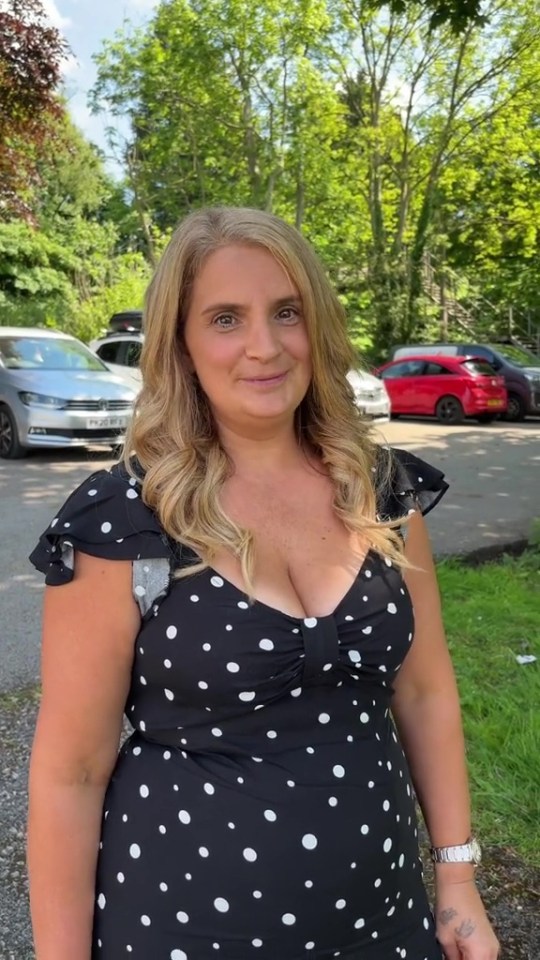 a woman in a black and white polka dot dress is standing in a parking lot