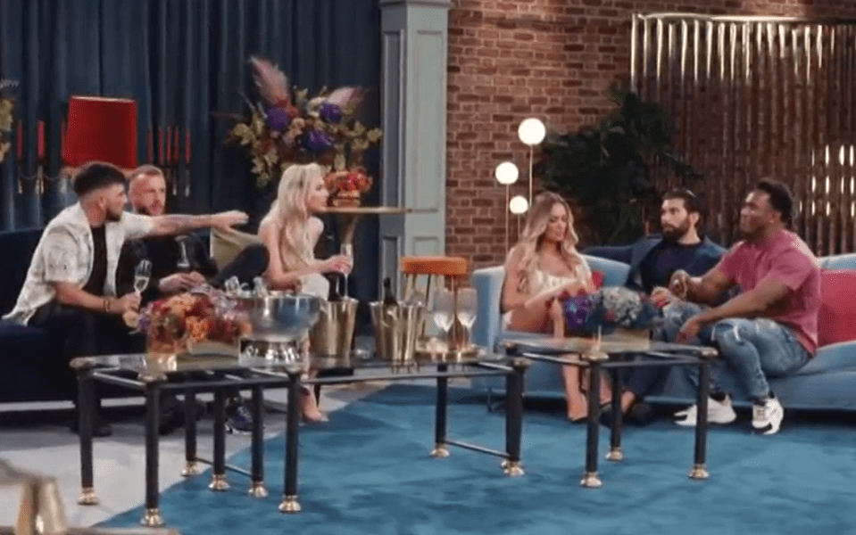 a group of people are sitting around a table in a living room