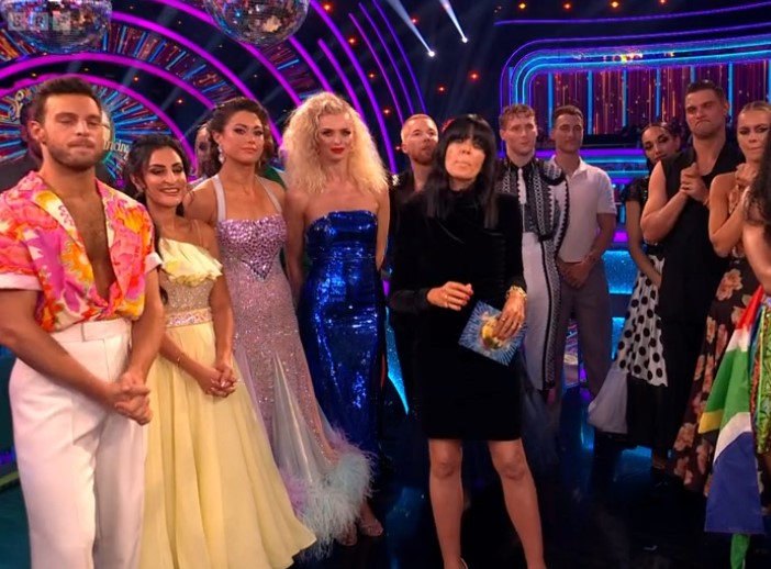 a group of people standing on a stage including a woman in a black dress