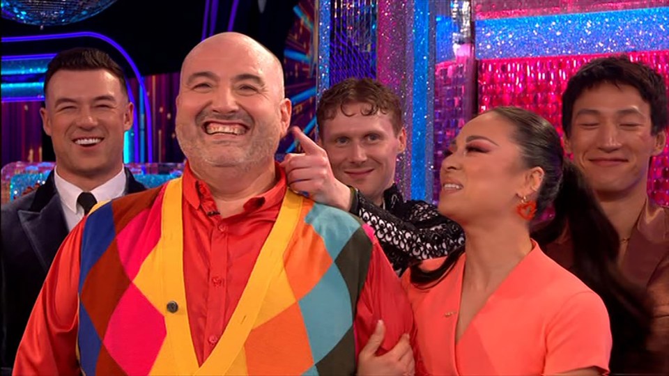 a group of people are posing for a picture and one of them is wearing a colorful vest