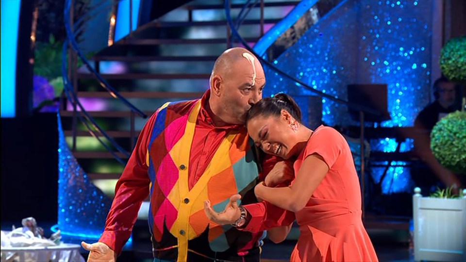 a man in a colorful vest kisses a woman on the cheek