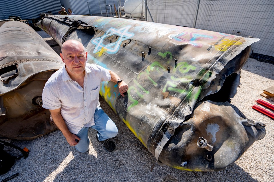 a man kneeling next to a large pipe with graffiti on it