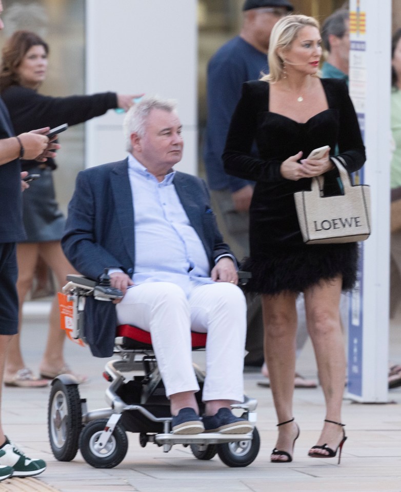 a man in a wheelchair next to a woman with a loewe bag