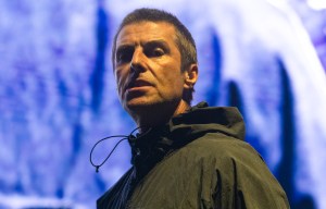 a man in a black jacket stands in front of a large screen