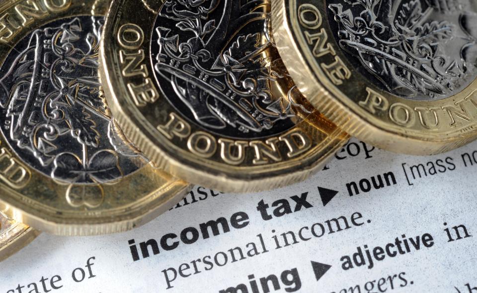 three one pound coins sit on top of a dictionary page