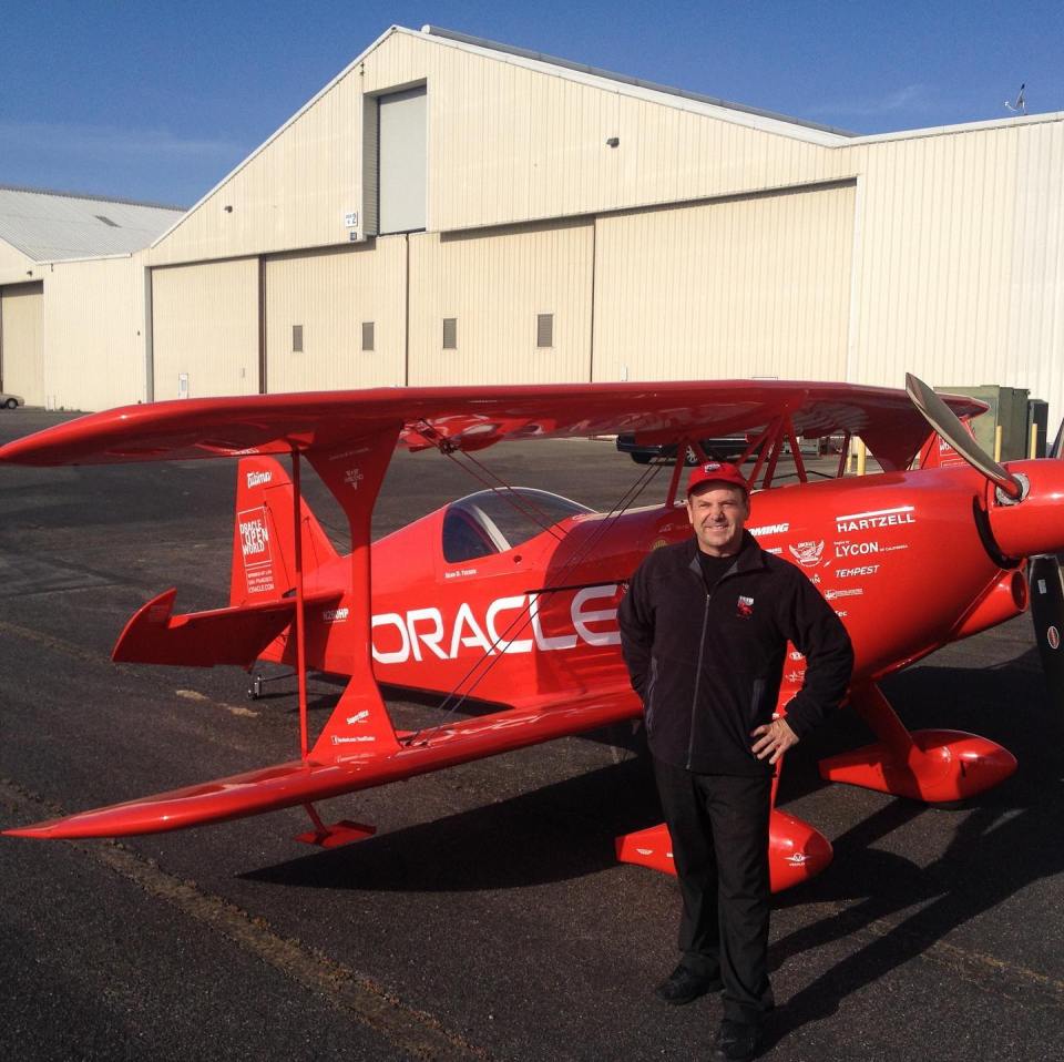 a man stands in front of a red oracle plane
