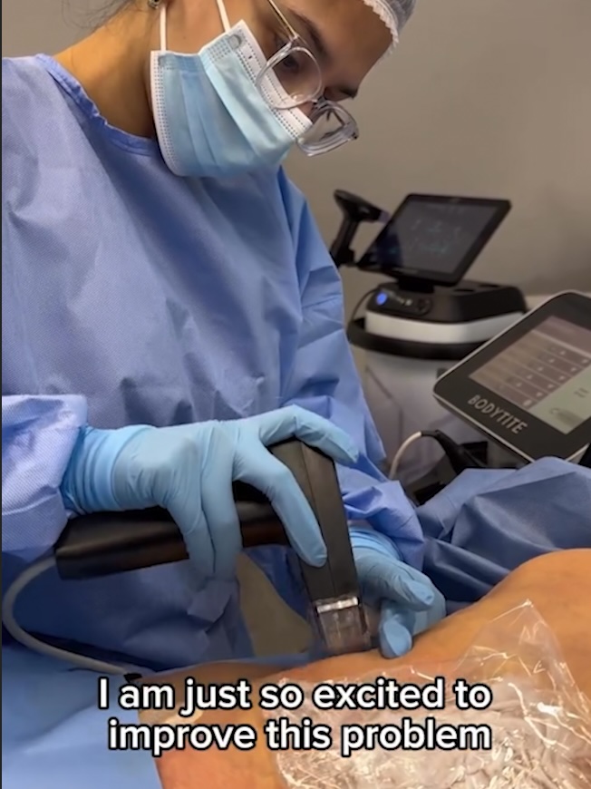 a woman wearing a mask and gloves is using a bodytite machine