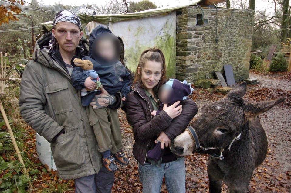 a man and a woman holding a baby standing next to a donkey