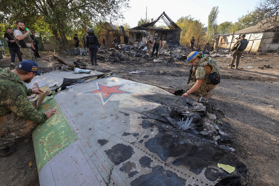 soldiers looking at a plane wing with a red star on it
