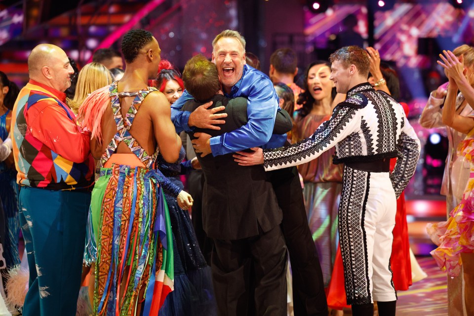 a man in a blue shirt is hugging another man