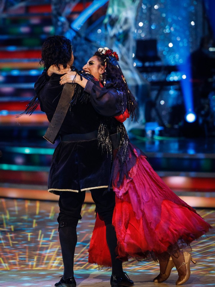 a woman in a red dress is dancing with a man in a black outfit