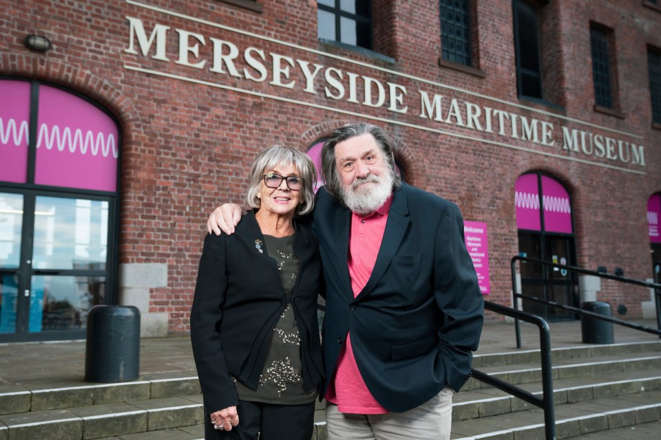 a man and woman stand in front of the merseyside maritime museum