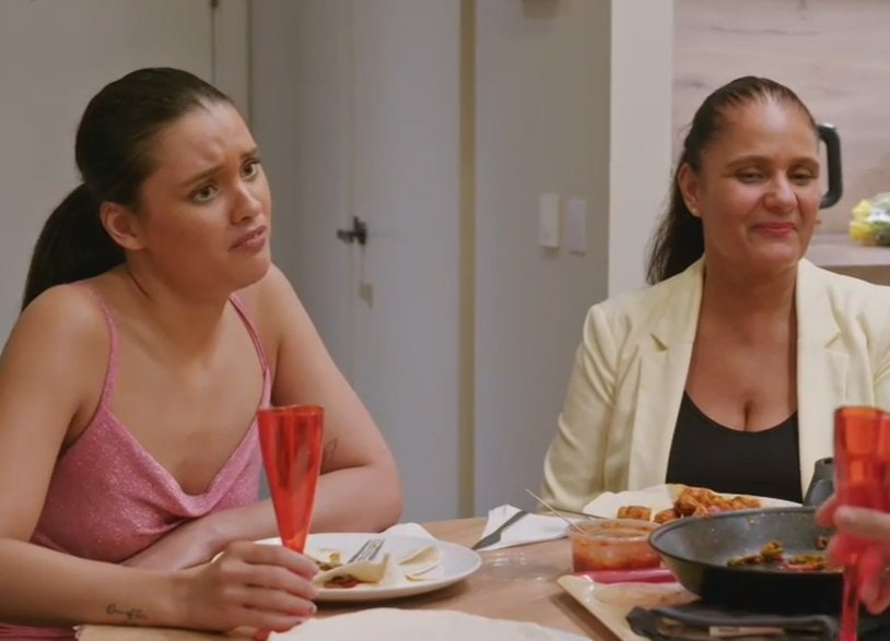 two women sit at a table with a plate of food and a glass of wine