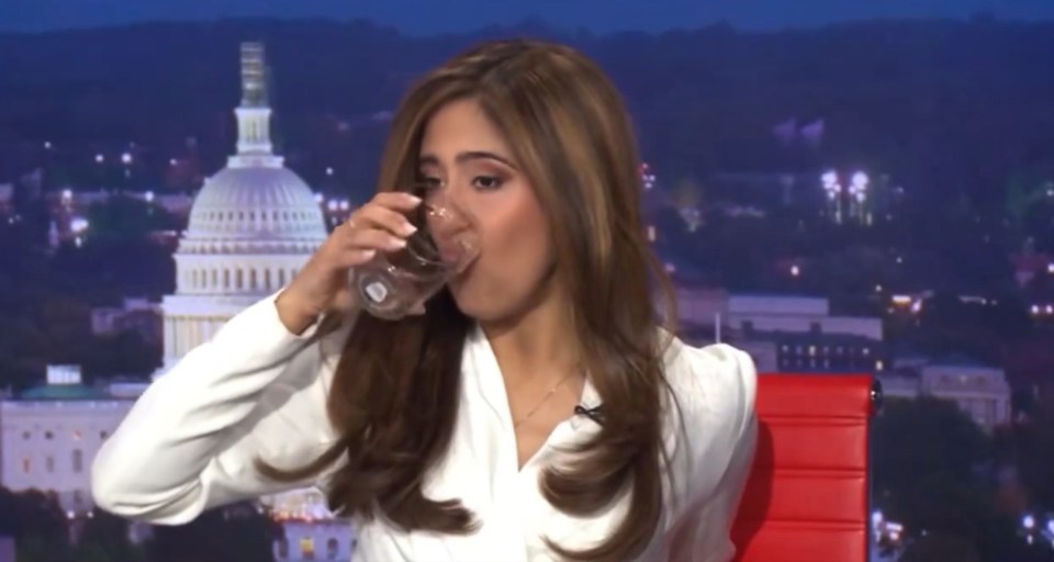 a woman drinking a glass of water in front of the capitol building