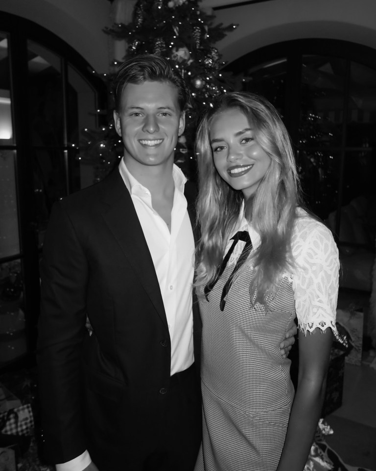 a man and a woman pose for a picture in front of a christmas tree