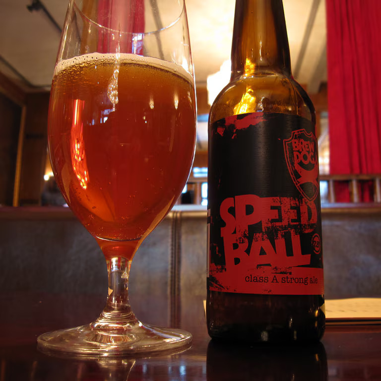 a bottle of speed ball class a strong ale next to a full glass