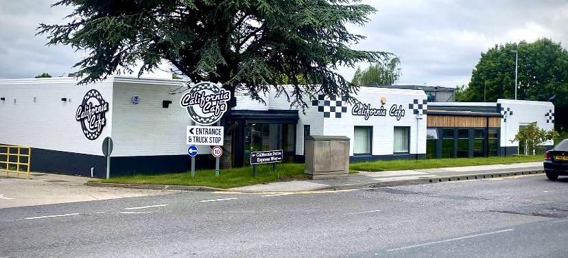 a white and black building with a sign on the side of it that says `` entrance & truck stop '' .