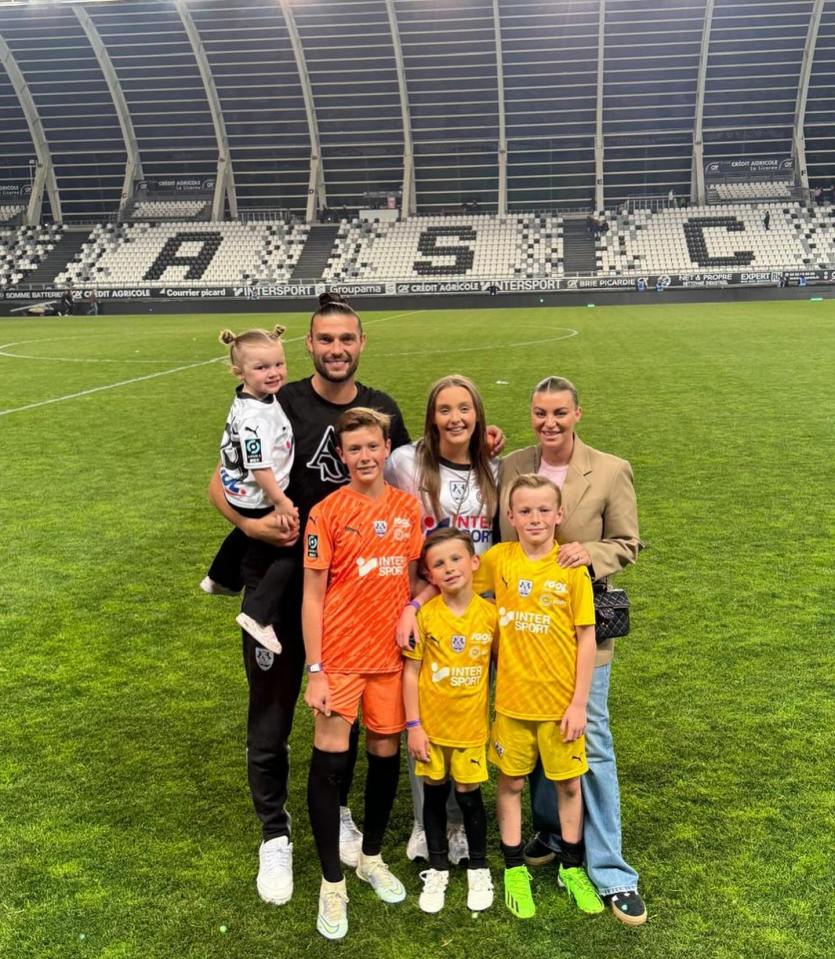a family posing for a picture on a soccer field with the letter a in the background
